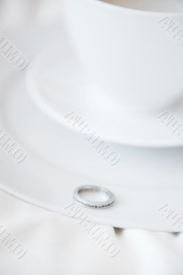 Closeup photo of proposal ring on white plate of coffee cup and 