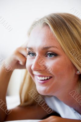 Portrait of beautiful smiling woman on bed at bedroom watching t