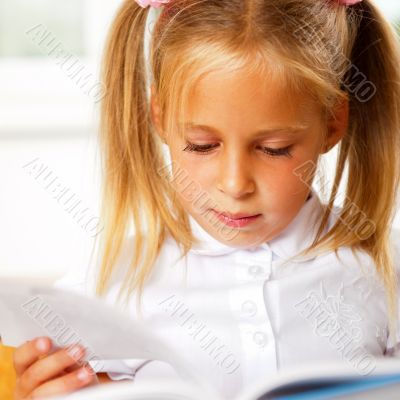 Image of smart child reading interesting book in classroom