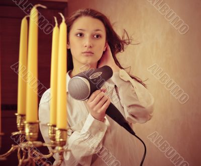 Beautiful woman drying her hair with hairdryer