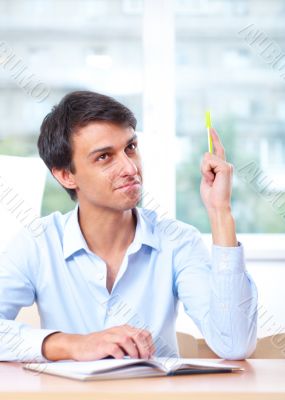 Businessman sitting indoors and writing plan in his diary