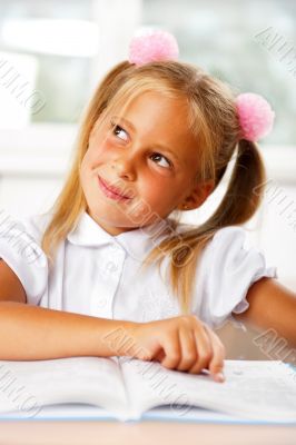 Image of smart child reading interesting book in classroom