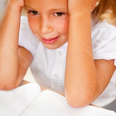 Image of smart child reading interesting book in classroom