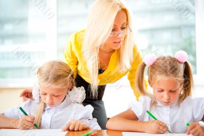 Young pretty teacher helping to her students to make exercise in