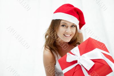 Young happy girl in Christmas hat. Standing indoors and holding 