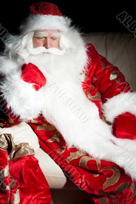 Santa sitting with a sack indoor at dark night room
