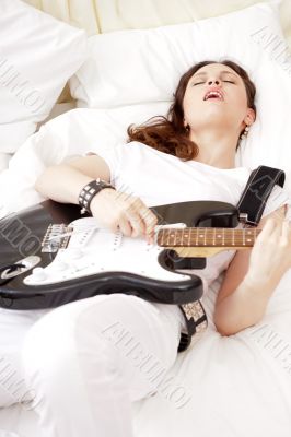 Teen girl holding a guitar like a rock star and enjoying playing