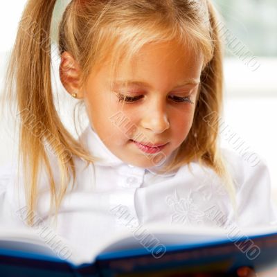 Image of smart child reading interesting book in classroom