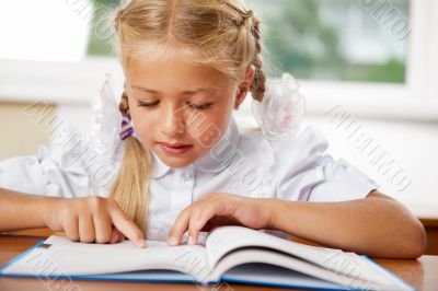 Portrait of a young girl in school at the desk.