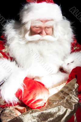 Santa sitting at the Christmas room and looking into the sack