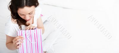 Portrait of young beautiful awake woman with gifts on bed at bed