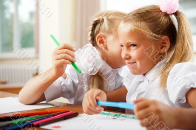 Two little girls gossip in classroom