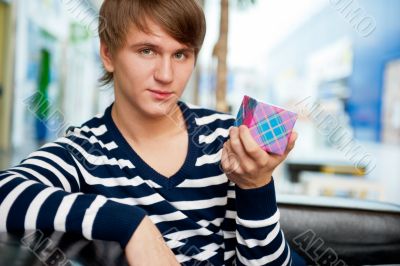 Portrait of young man inside shopping mall sitting relaxed on co