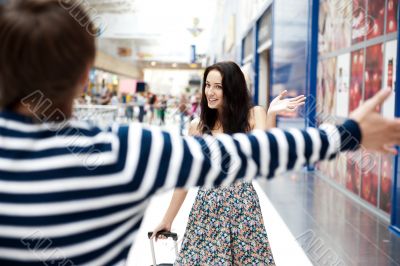 Young man meeting his girlfriend with opened arms at airport arr