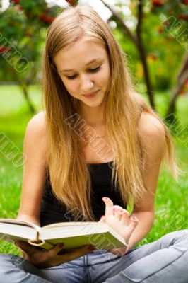 Beautiful female student outdoors with a book at campus park