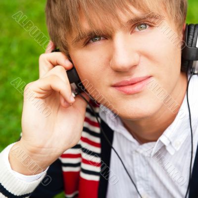 Student outside sitting on green grass and listening music via h