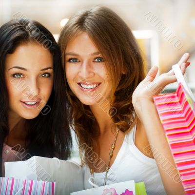 Two excited shopping woman resting on bench at shopping mall loo