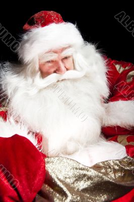 Santa sitting at the Christmas room and looking into the sack