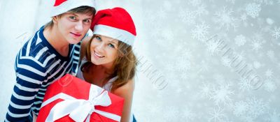 Portrait of young pretty couple standing indoors wearing Santa C