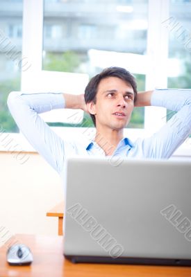 A young man sitting in front of a laptop in his office