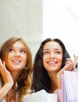 Two excited shopping woman together inside shopping mall. Horizo