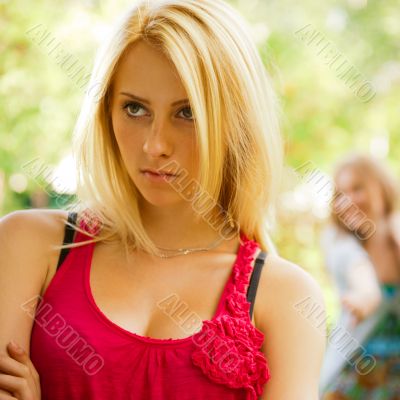 Upset teenage girl being jeered by group of the other young peop