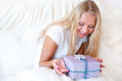 Bedroom surprise present - young happy woman in bedroom