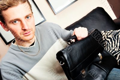 Happy young man sitting on sofa at home 
