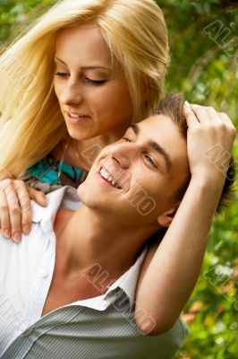 Portrait of love couple embracing outdoor in park looking happy