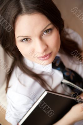 Portrait of a happy young brunette woman holding book