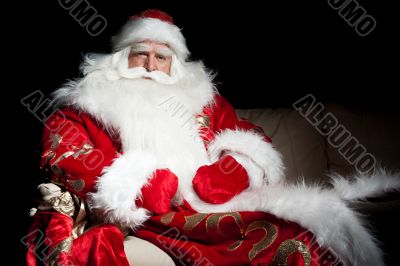 Santa sitting with a sack indoor at dark night room