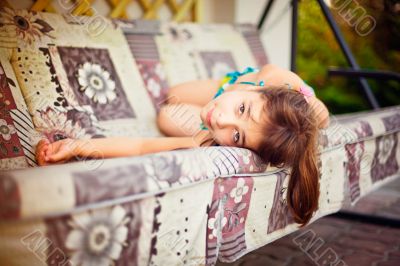 Artistic lifestyle photo of little girl leaning on swing sofa ou