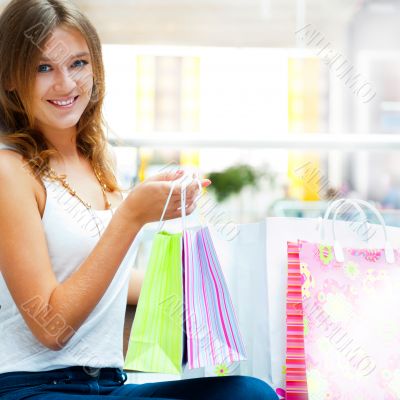 Happy shopping woman with bags and smiling. She is shopping insi