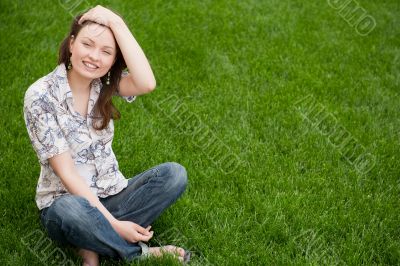 Full length of pretty young woman resting on grass and smiling