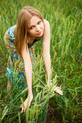 Portrait of young woman stands in a field of wheat with joy