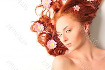 Beautiful woman with flowers in her red hair she is lying relaxe