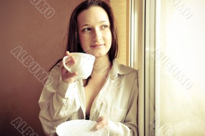 Portrait of cosy young girl standing near a window at home