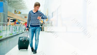 Portrait of a successful young man walking with travel bag at mo