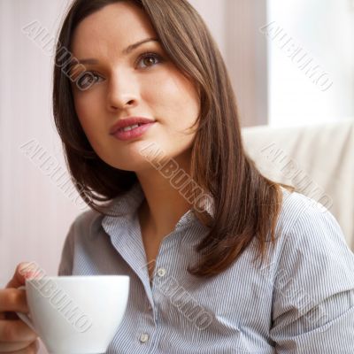 Young woman at home sipping tea from a cup