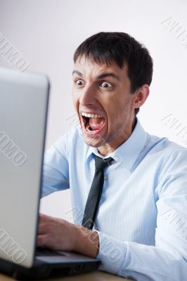 Attractive young man working with a laptop at his office. He is 