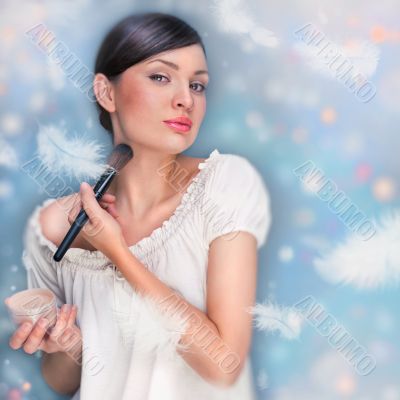 Portrait of a Beautiful woman applying makeup with brush on her 