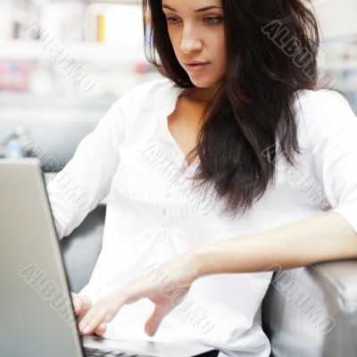 Portrait of a beautiful young woman working on laptop while sitt