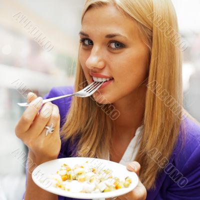 Closeup portrait of an attractive young woman eating fruit salad