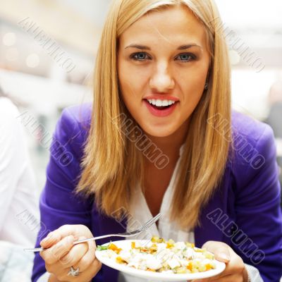 Closeup portrait of an attractive young woman eating fruit salad