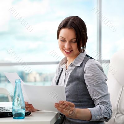 Beautiful business woman looking at papers she holding in her ar