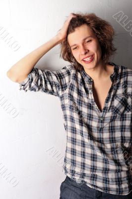 Handsome man with funky hairstyle casually leaning against the w