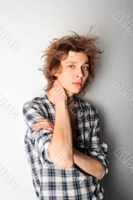 Handsome man with funky hairstyle casually leaning against the w