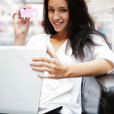 Portrait of a beautiful young woman working on laptop while sitt