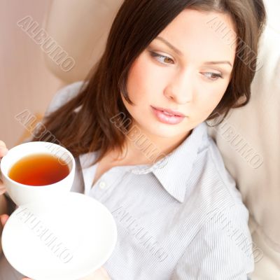 Young woman at home sipping tea from a cup