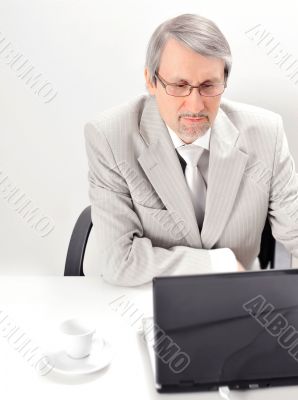 Portrait of an older businessman with a computer and a cup.